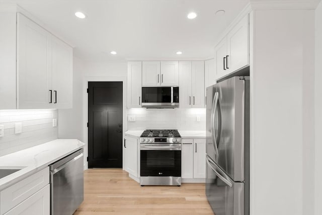 63 Oak St Unit 2, Somerville, MA 02143 - kitchen featuring stainless steel appliances, tasteful backsplash, light wood-style flooring, white cabinets, and recessed lighting