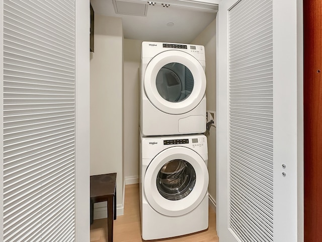 laundry room with stacked washer / dryer and light hardwood / wood-style flooring