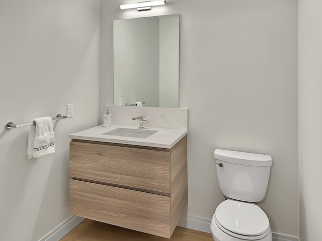 bathroom with hardwood / wood-style flooring, toilet, and vanity