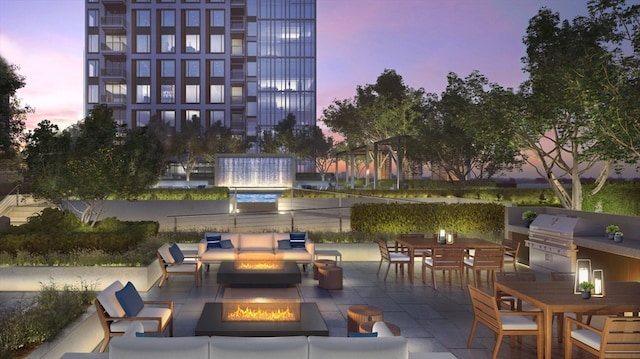 patio terrace at dusk featuring grilling area and an outdoor living space with a fire pit