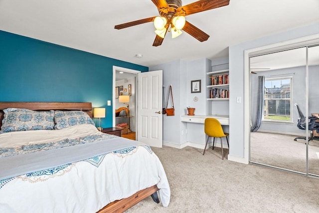 bedroom with a closet, baseboards, built in desk, a ceiling fan, and carpet