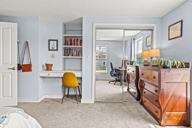 carpeted office space featuring baseboards and built in desk