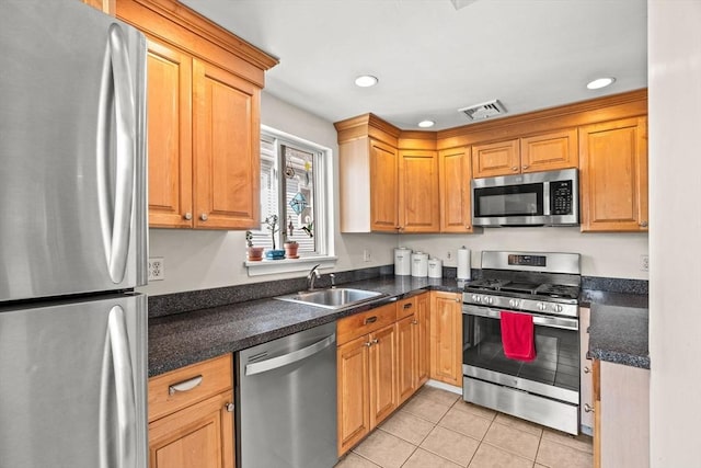 kitchen with visible vents, light tile patterned flooring, dark countertops, a sink, and appliances with stainless steel finishes