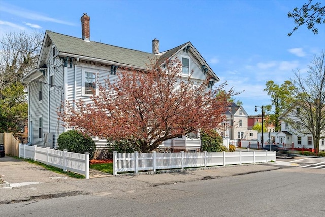 view of front of house with a residential view, fence, and a chimney
