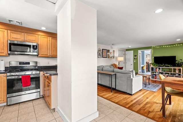 kitchen featuring open floor plan, appliances with stainless steel finishes, dark countertops, and light tile patterned floors