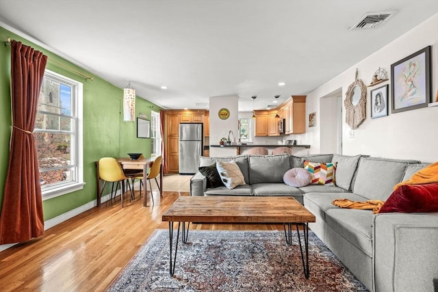 living area with recessed lighting, baseboards, visible vents, and light wood-style flooring
