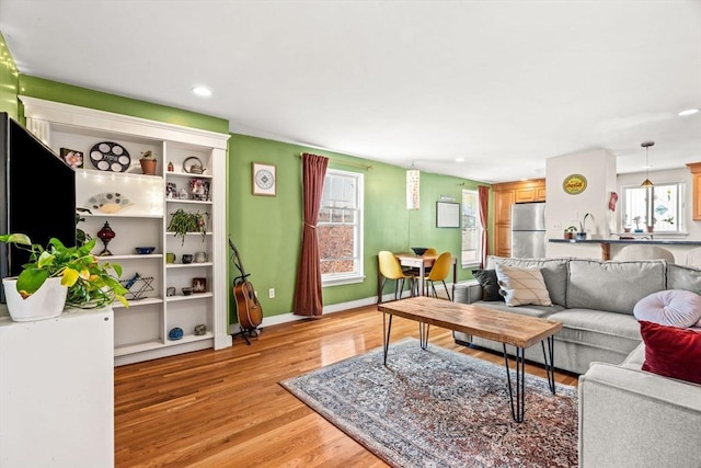 living room featuring recessed lighting, baseboards, and light wood-type flooring