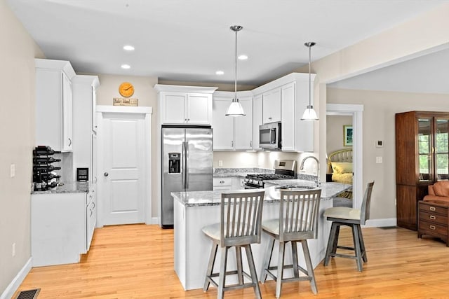 33 Inkberry Ln, Plymouth, MA 02360 - kitchen featuring appliances with stainless steel finishes, a peninsula, light stone countertops, light wood finished floors, and baseboards