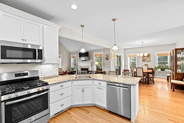 33 Inkberry Ln, Plymouth, MA 02360 - kitchen with appliances with stainless steel finishes, a peninsula, light wood-style floors, white cabinetry, and a fireplace