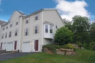 view of front of home featuring driveway, an attached garage, and a front lawn