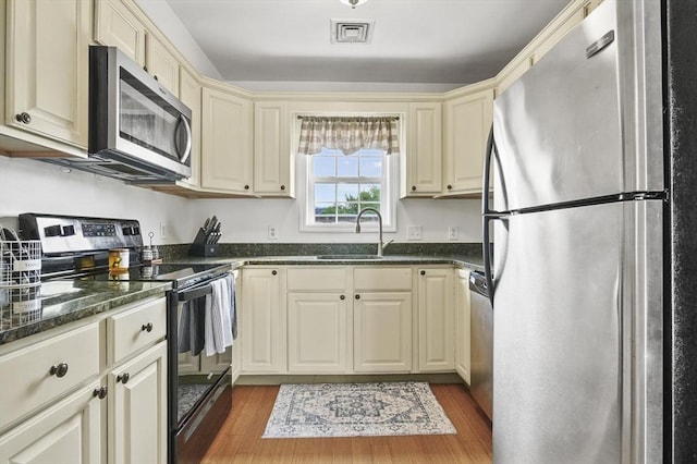 226-236 River St Unit 5, Haverhill, MA 01832 - kitchen with stainless steel appliances, cream cabinets, light wood-style flooring, a sink, and dark stone counters
