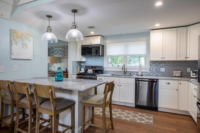 kitchen featuring sink, hanging light fixtures, stainless steel appliances, light stone countertops, and white cabinets