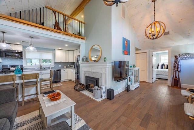 living room with hardwood / wood-style flooring, a healthy amount of sunlight, an inviting chandelier, and beam ceiling