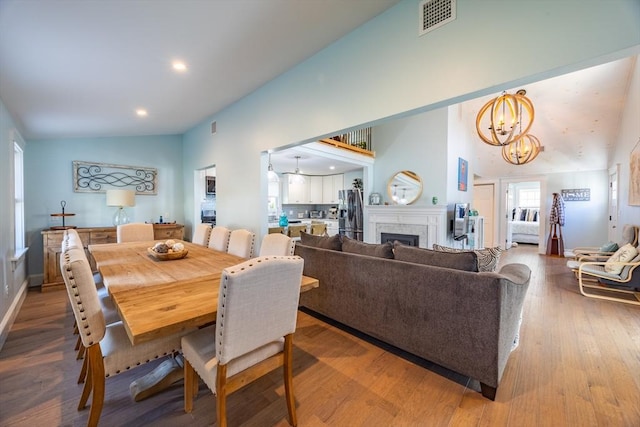 dining area with hardwood / wood-style flooring, vaulted ceiling, and a notable chandelier