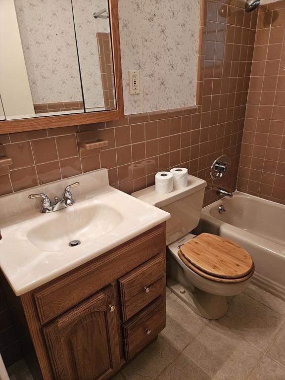 59 Tanbark Rd, Sudbury, MA 01776 - bathroom featuring wallpapered walls, vanity, toilet, shower / bathtub combination, and tile walls