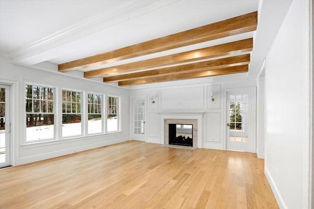 unfurnished living room featuring beamed ceiling, light wood-type flooring, a fireplace with flush hearth, and baseboards