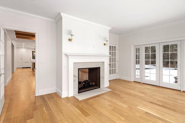 unfurnished living room featuring a fireplace with flush hearth, baseboards, ornamental molding, french doors, and light wood-type flooring