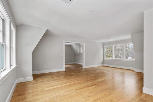 additional living space featuring baseboards, vaulted ceiling, and light wood finished floors