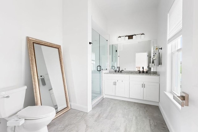 full bathroom featuring toilet, a stall shower, vanity, and baseboards