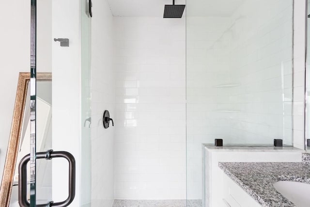 full bath featuring tiled shower and vanity