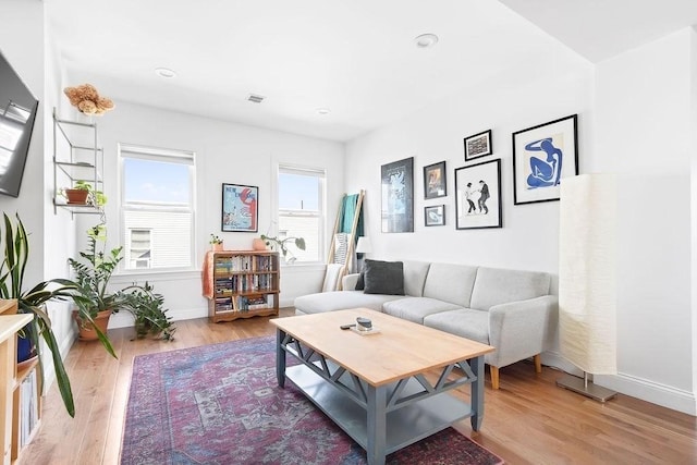 living area with light wood-type flooring, baseboards, and recessed lighting
