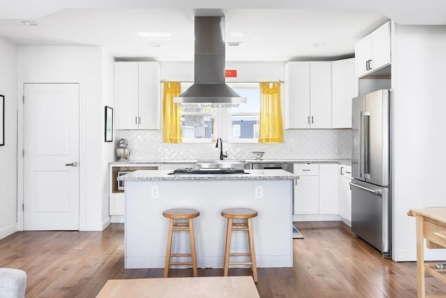 kitchen featuring appliances with stainless steel finishes, wood finished floors, tasteful backsplash, white cabinets, and recessed lighting