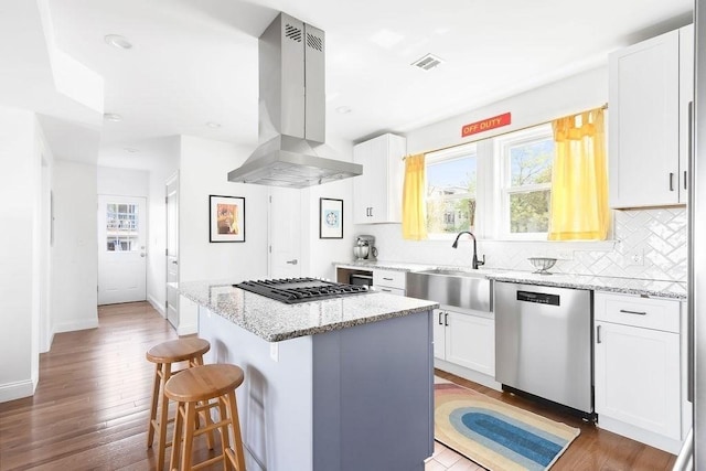 kitchen with dishwasher, a sink, island range hood, gas stovetop, and a kitchen breakfast bar