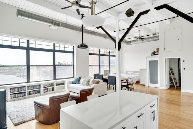 living room with a wealth of natural light, beamed ceiling, and light wood-type flooring