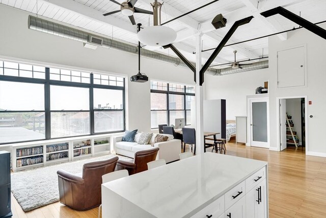 dining space featuring a towering ceiling, light hardwood / wood-style flooring, plenty of natural light, and ceiling fan