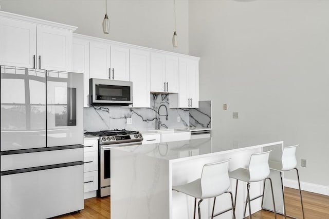 kitchen featuring sink, white cabinets, appliances with stainless steel finishes, and hanging light fixtures