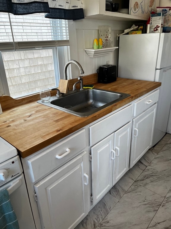 kitchen featuring white cabinets, sink, white appliances, and wood counters