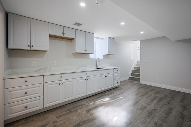 kitchen with light stone counters, sink, dark hardwood / wood-style floors, and white cabinets