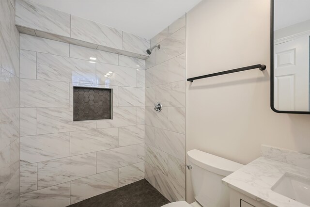 bathroom with toilet, vanity, and tiled shower