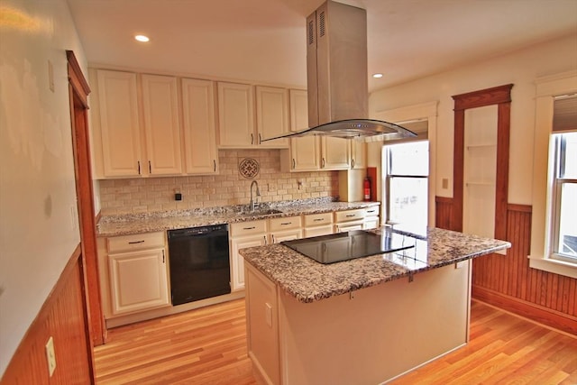 kitchen with light wood-style floors, wainscoting, a sink, island range hood, and black appliances