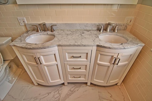 full bathroom featuring marble finish floor, a sink, and double vanity