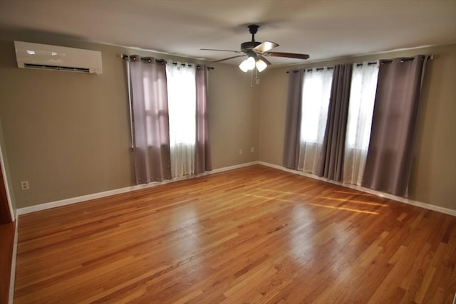 empty room featuring a wall mounted AC, plenty of natural light, and wood finished floors