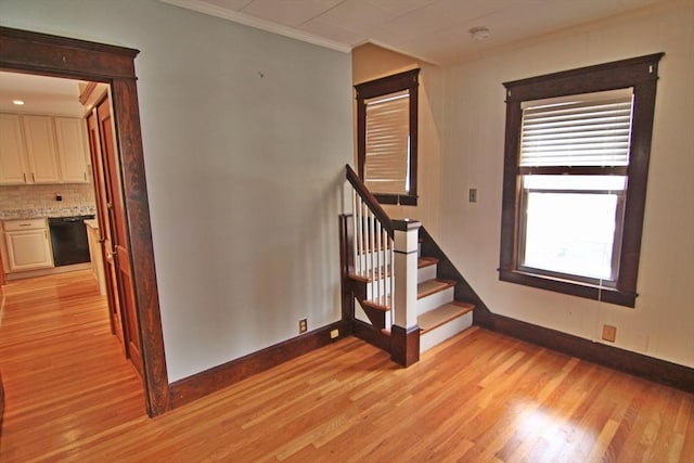 stairs featuring crown molding, baseboards, and wood finished floors