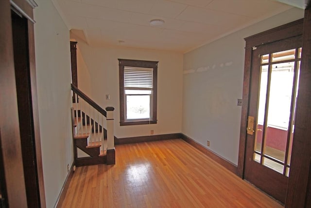 empty room with baseboards, stairway, and wood finished floors