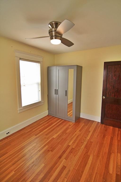 unfurnished bedroom with light wood-style flooring, baseboards, and a ceiling fan