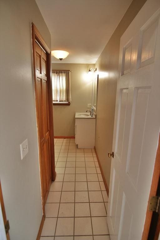 hallway featuring light tile patterned floors, a sink, and baseboards