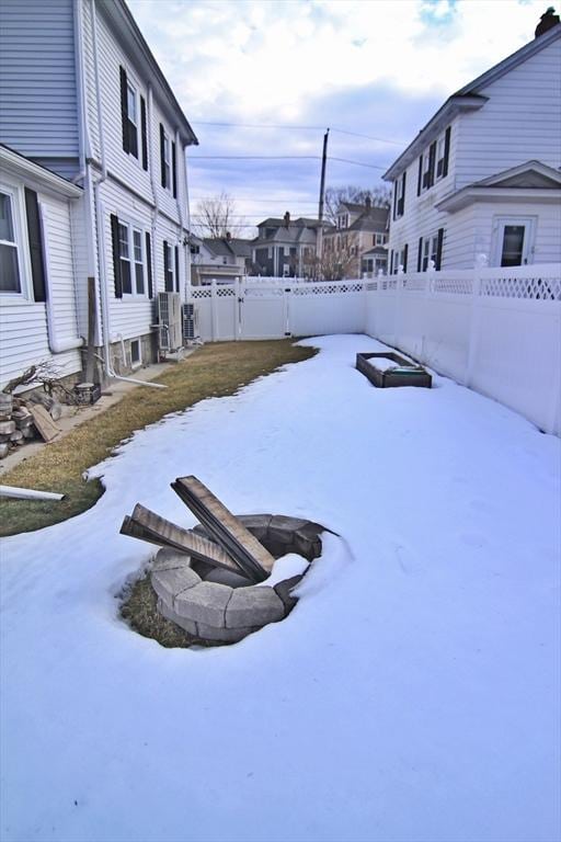 snowy yard with a fenced backyard, a residential view, and a fire pit