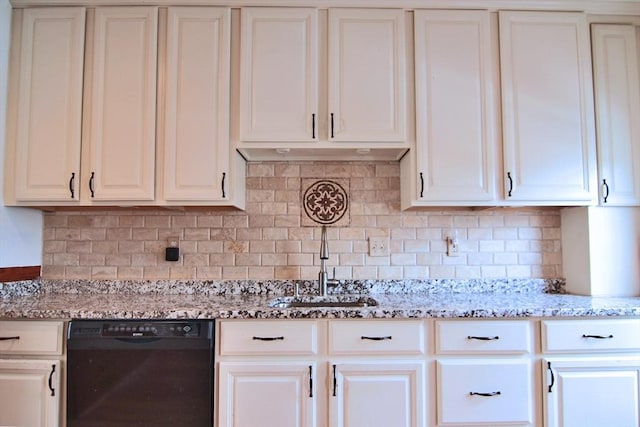 kitchen with tasteful backsplash, black dishwasher, white cabinets, and light stone countertops