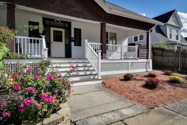 entrance to property featuring a porch and fence