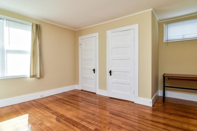 unfurnished bedroom featuring wood finished floors, baseboards, and ornamental molding