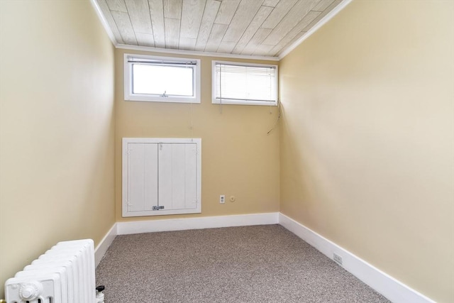 carpeted empty room with radiator heating unit, crown molding, wood ceiling, and baseboards