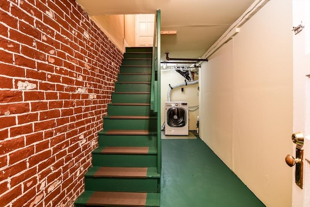 stairs featuring washer / clothes dryer and brick wall