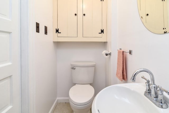 bathroom with a sink, toilet, and baseboards