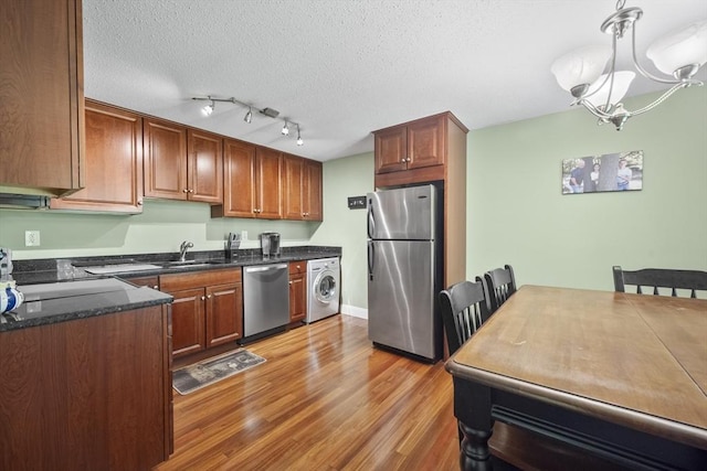 1410 Skyline Dr Unit 11, Lowell, MA 01854 - kitchen with appliances with stainless steel finishes, washer / dryer, a sink, a chandelier, and light wood finished floors