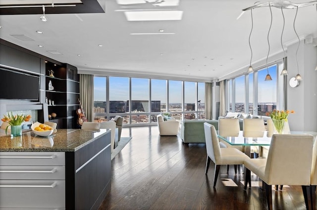 dining space with a view of city, dark wood finished floors, and a wall of windows