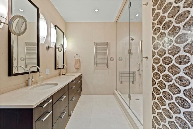 bathroom with a stall shower, a towel warmer, double vanity, tile patterned floors, and recessed lighting